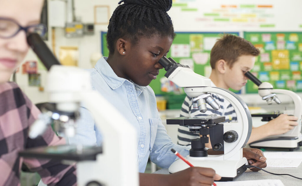 Group Of Pupils Using Microscopes In Science Class